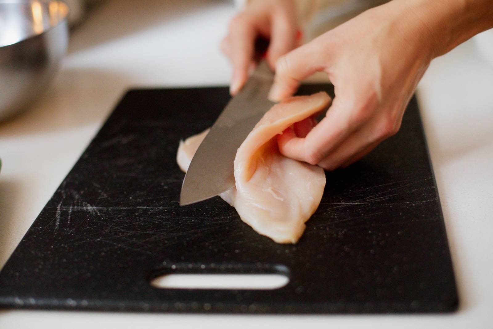 Slicing chicken in half lengthwise.