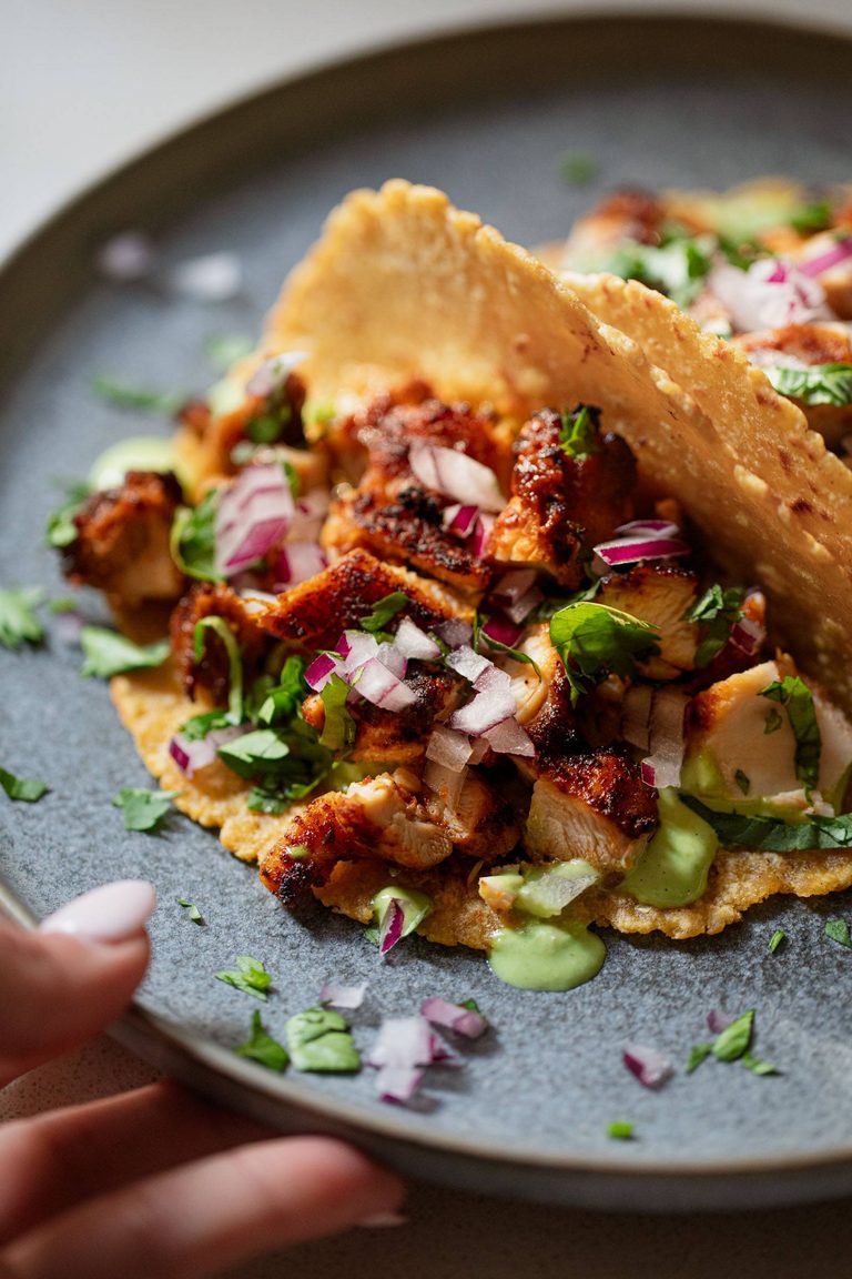 Chicken tacos with green sauce on top.
