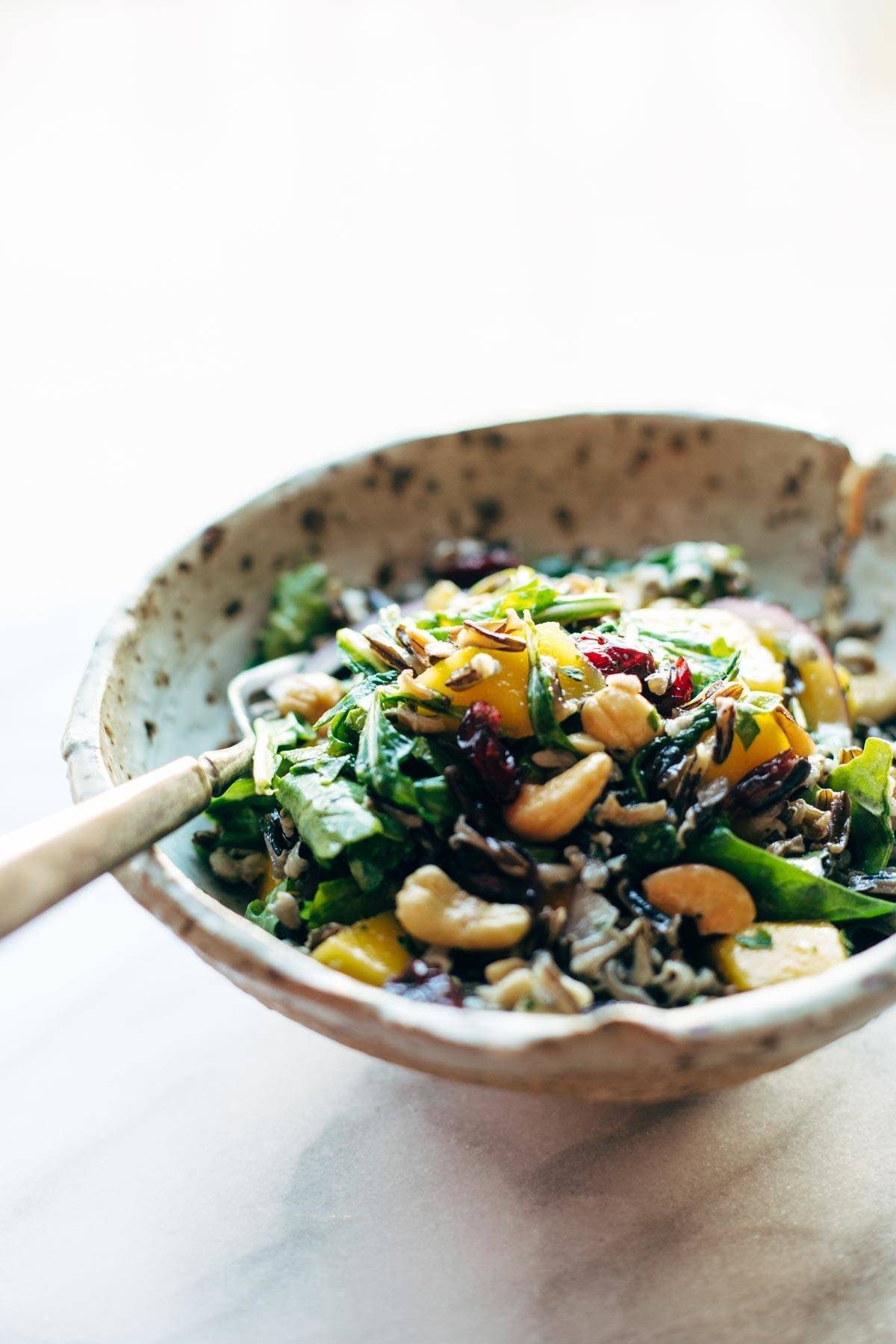 Easy Thanksgiving Salad - arugula, wild rice, cashews, dried cranberries, red onions, and a lemon dressing that shakes up easily in a jar. | pinchofyum.com